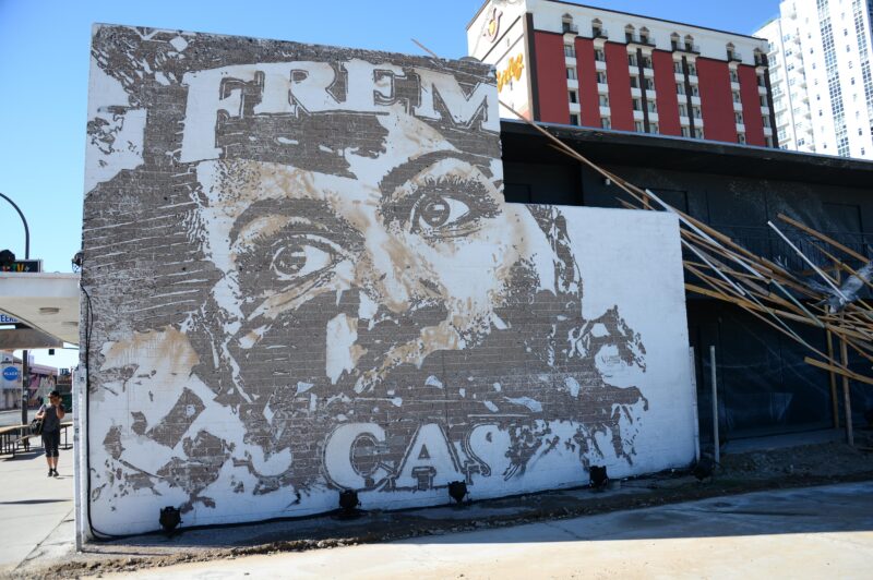 A mural by artist Vhils, featuring a rustic brushstroke image of a woman's eyes - with torn lettering behind her.