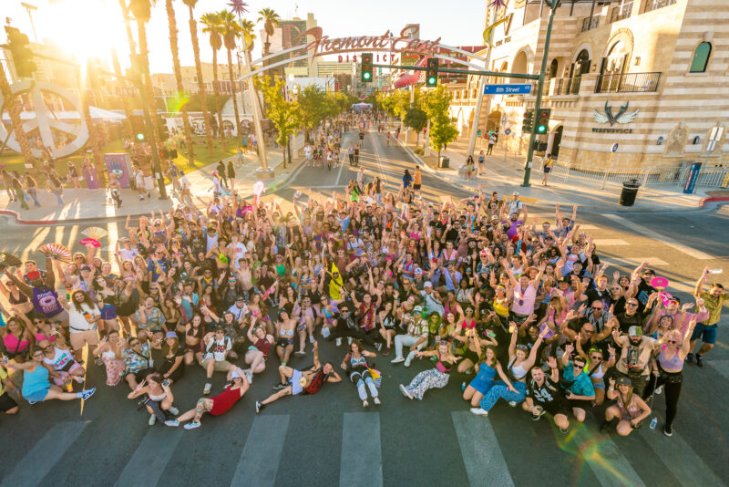 An aerial shot of Downtown Las Vegas captured during Life is Beautiful Music Festival. The sunset image features a large crowd gathered to celebrate the festival, smiling for the camera.